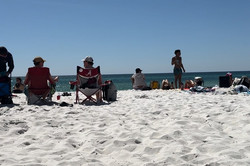 Hier sieht man einen Strand und Meer. Zahlreiche Menschen liegen im Sand. 